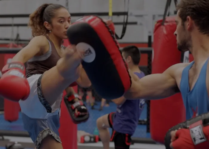 A kick lands on the pads during partner drills